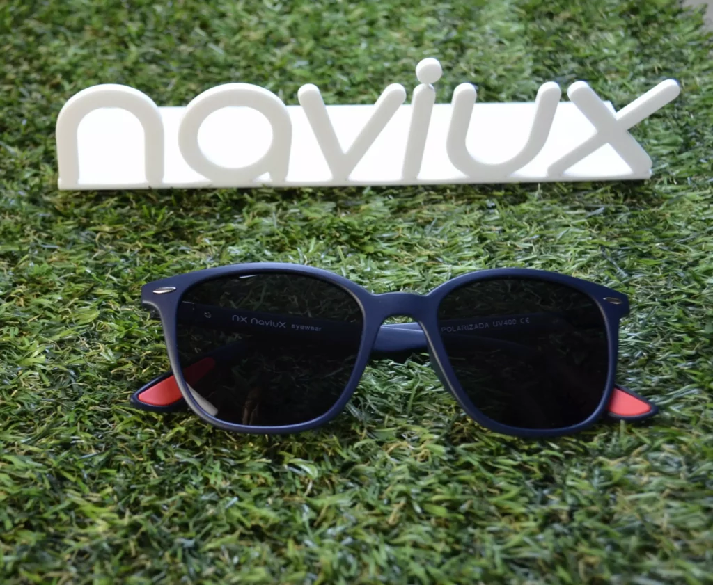 Gafas de sol polarizadas Naviux sobre césped artificial con logo de la marca naviuxal fondo